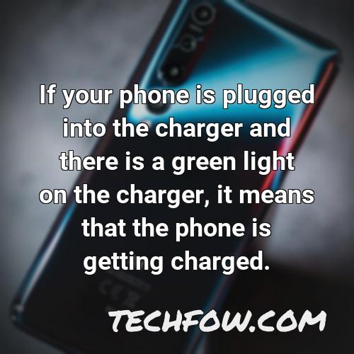 if your phone is plugged into the charger and there is a green light on the charger it means that the phone is getting charged