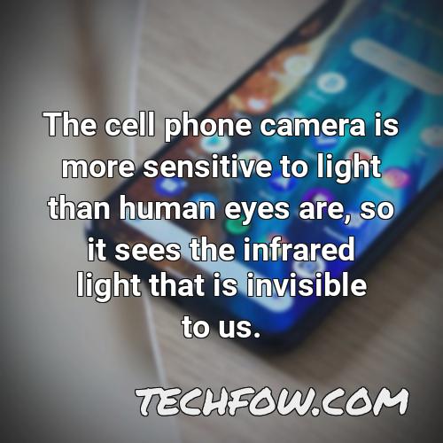 the cell phone camera is more sensitive to light than human eyes are so it sees the infrared light that is invisible to us