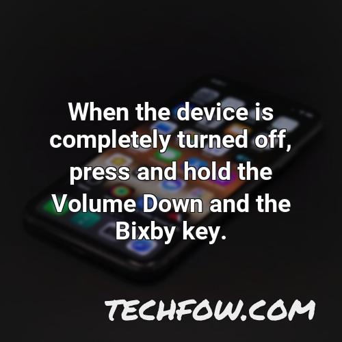 when the device is completely turned off press and hold the volume down and the bixby key