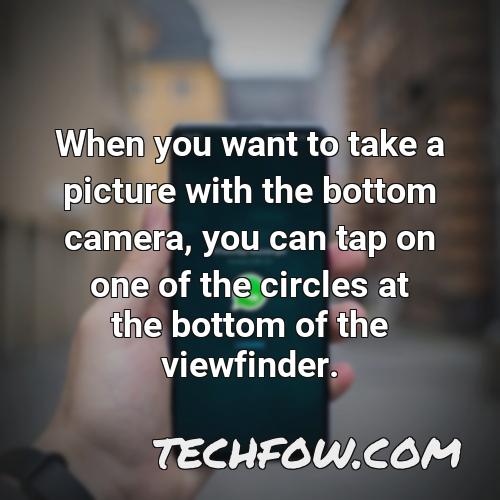 when you want to take a picture with the bottom camera you can tap on one of the circles at the bottom of the viewfinder