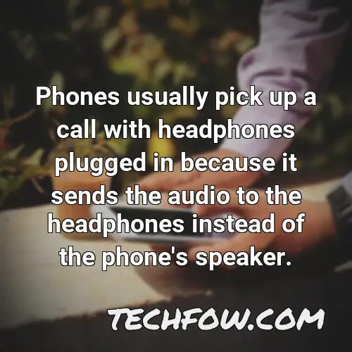 phones usually pick up a call with headphones plugged in because it sends the audio to the headphones instead of the phone s speaker
