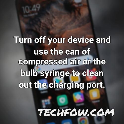 turn off your device and use the can of compressed air or the bulb syringe to clean out the charging port