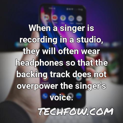 when a singer is recording in a studio they will often wear headphones so that the backing track does not overpower the singer s voice