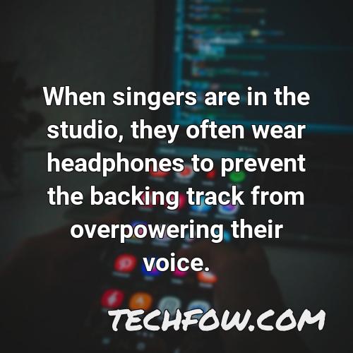 when singers are in the studio they often wear headphones to prevent the backing track from overpowering their voice