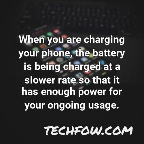when you are charging your phone the battery is being charged at a slower rate so that it has enough power for your ongoing usage